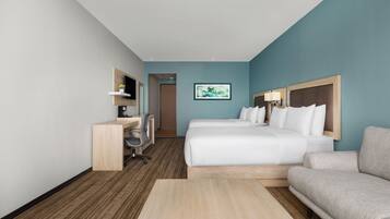 Una habitación de hotel con una cama, un escritorio, una silla, un sofá y un cuadro en la pared.