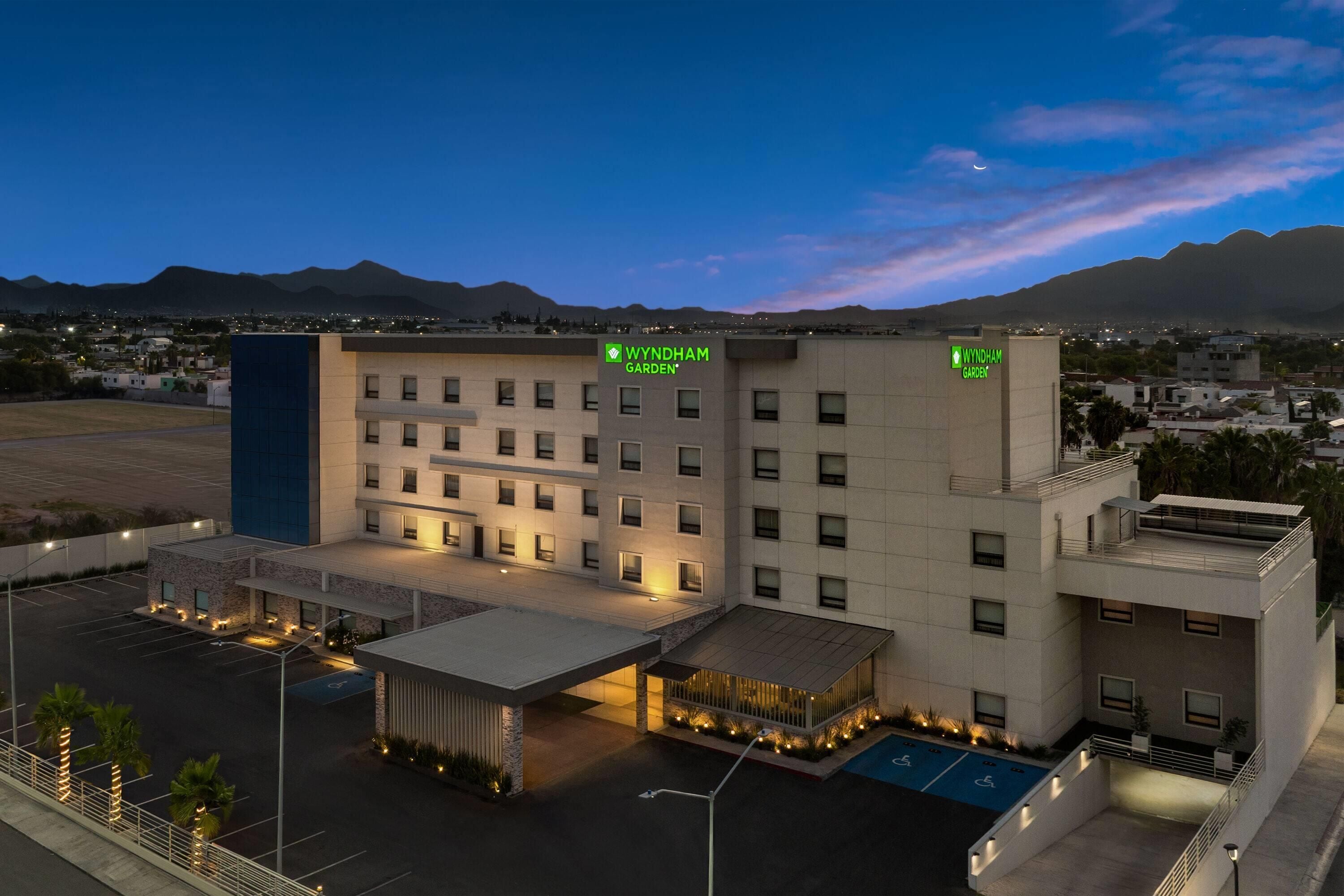 A hotel with a modern design, featuring a central courtyard and multiple parking spaces.
