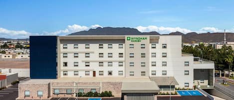 A Wyndham Garden hotel with a parking lot, a blue handicap parking space, and a mountain backdrop.