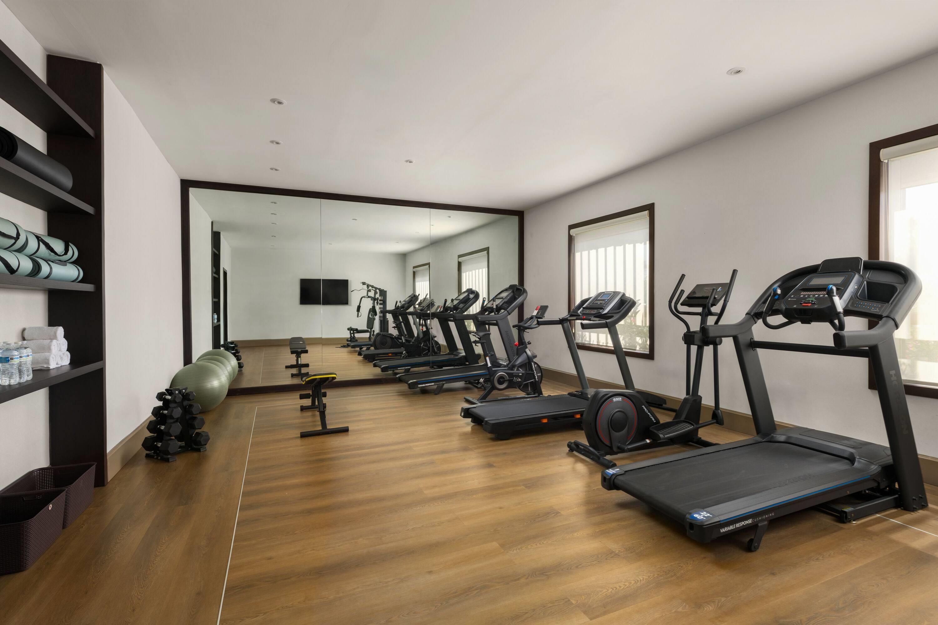 A gym with multiple treadmills, exercise balls, and dumbbells.