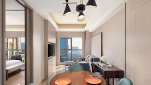 Una habitación de hotel moderna con comedor, sofá y televisor.