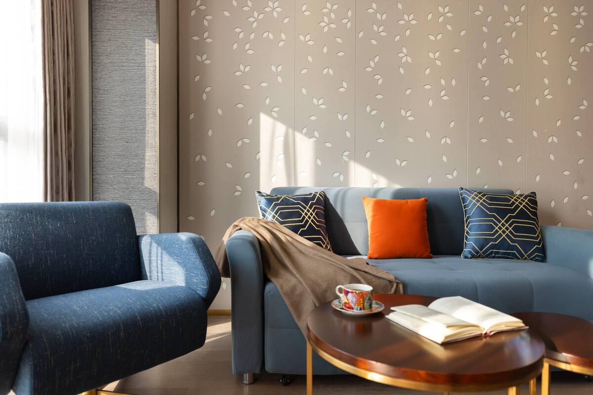 Een moderne woonkamer met een blauwe bank, een houten salontafel en een behang met een patroon.