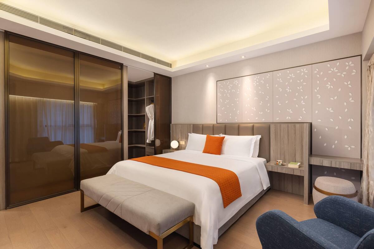 Een moderne hotelkamer met een groot bed, een zithoek, een kledingkast en een televisie.