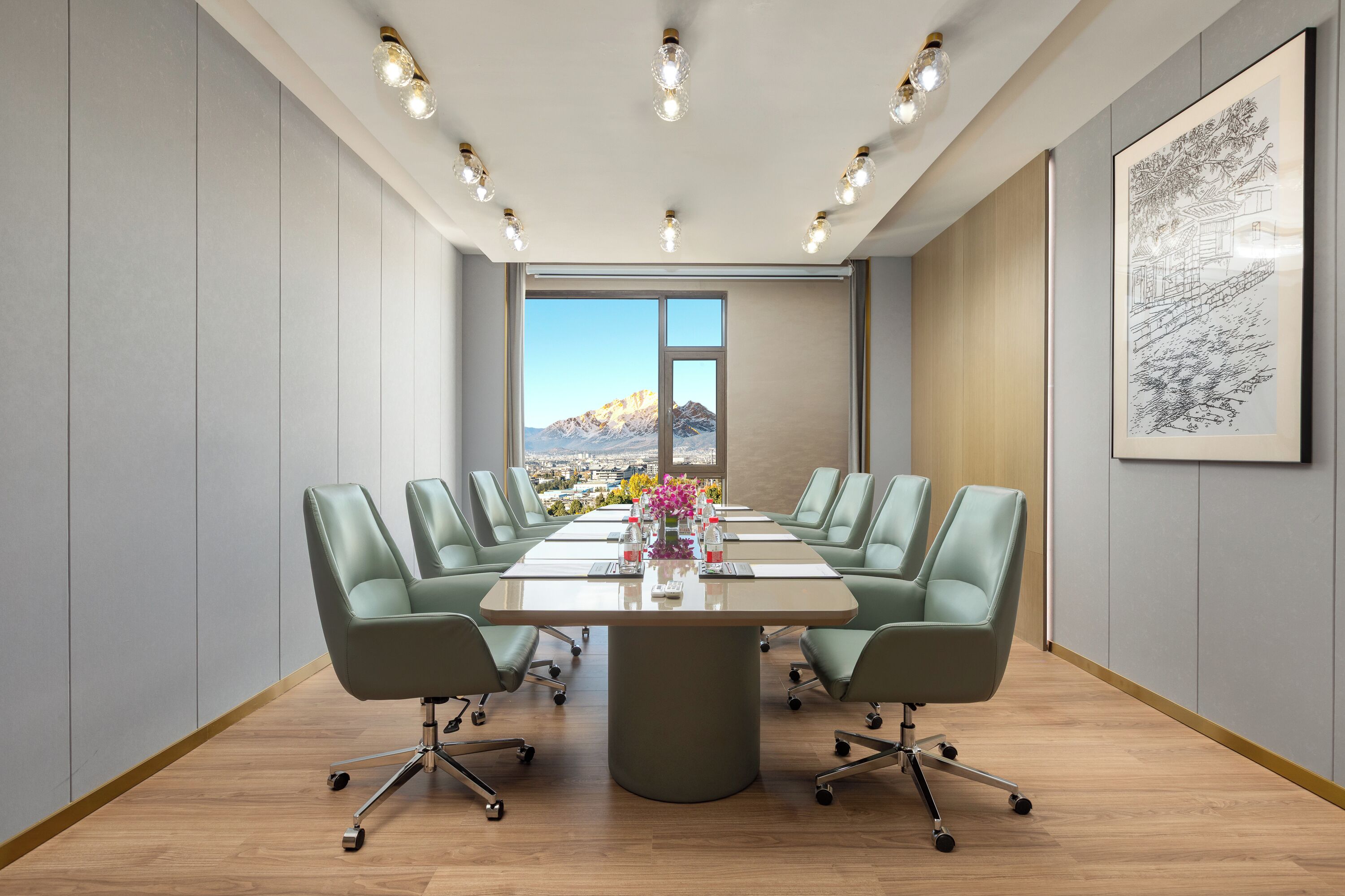Une salle de conférence dotée d’une grande table, de six chaises, d’un vase de fleurs et offrant une vue sur le paysage urbain grâce à une grande fenêtre.