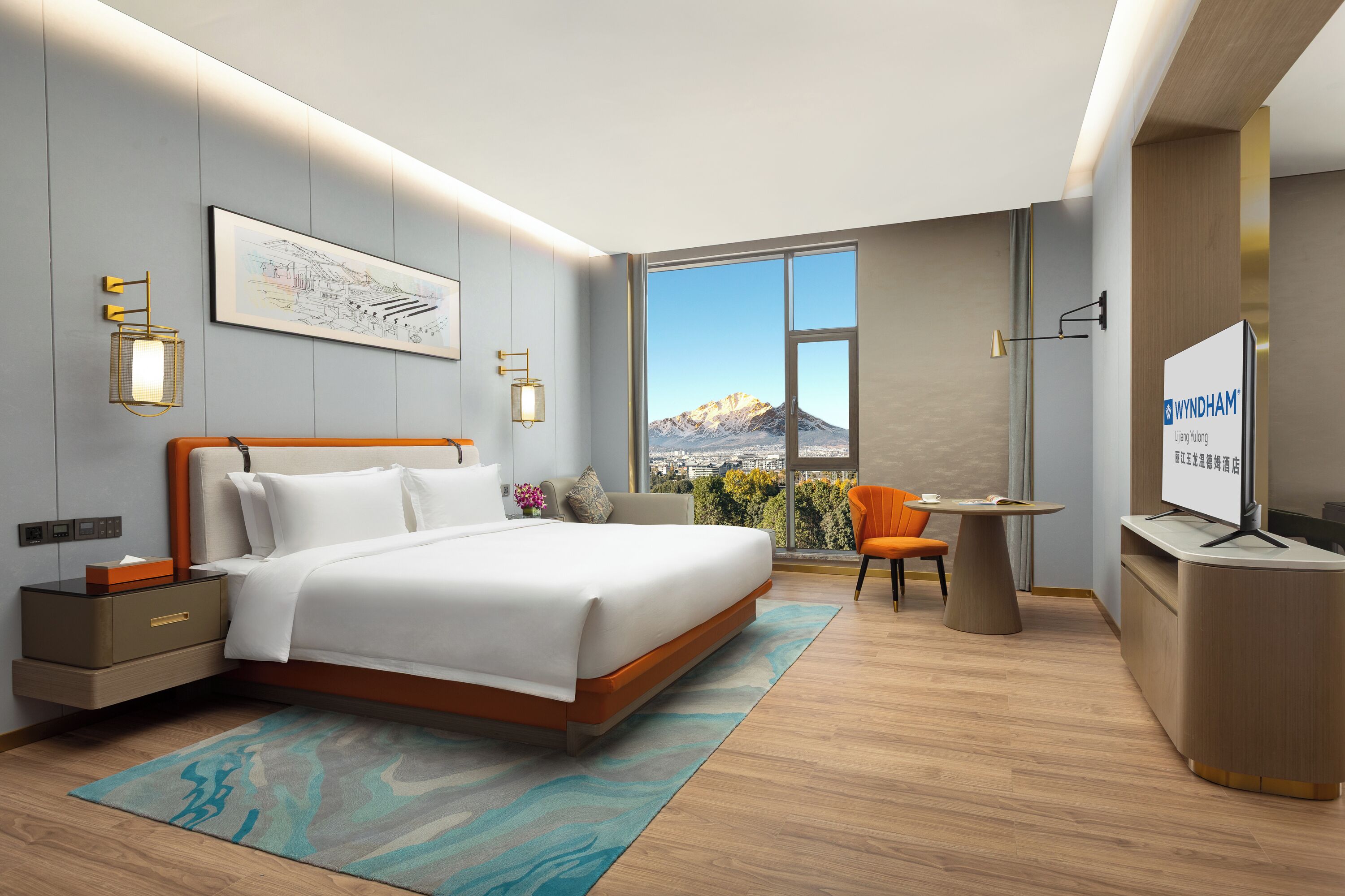 Quarto de hotel moderno com cama, mesa de cabeceira, televisão e escrivaninha com cadeira.