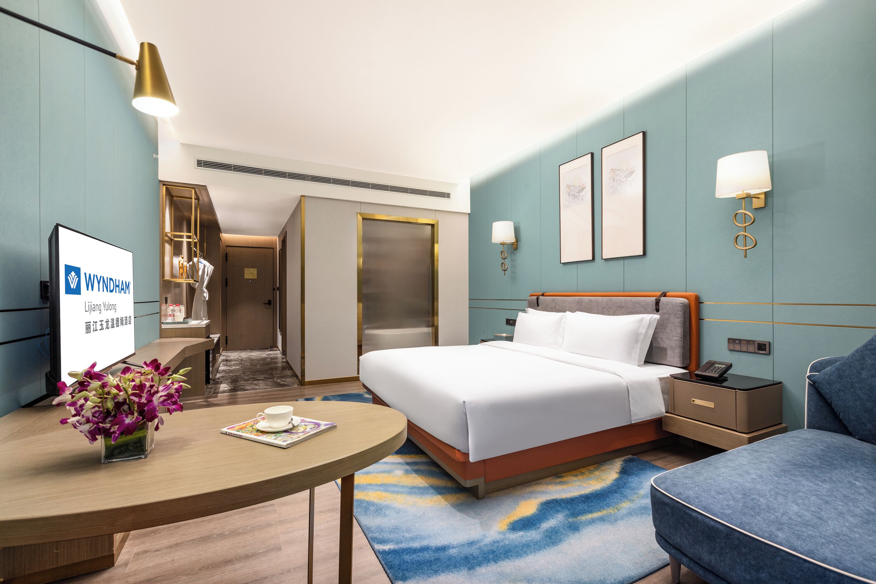 Una habitación de hotel con cama, mesita de noche, lámpara y escritorio con un florero.