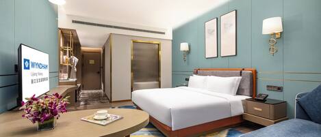 Una habitación de hotel con cama, mesita de noche, lámpara y escritorio con un florero.