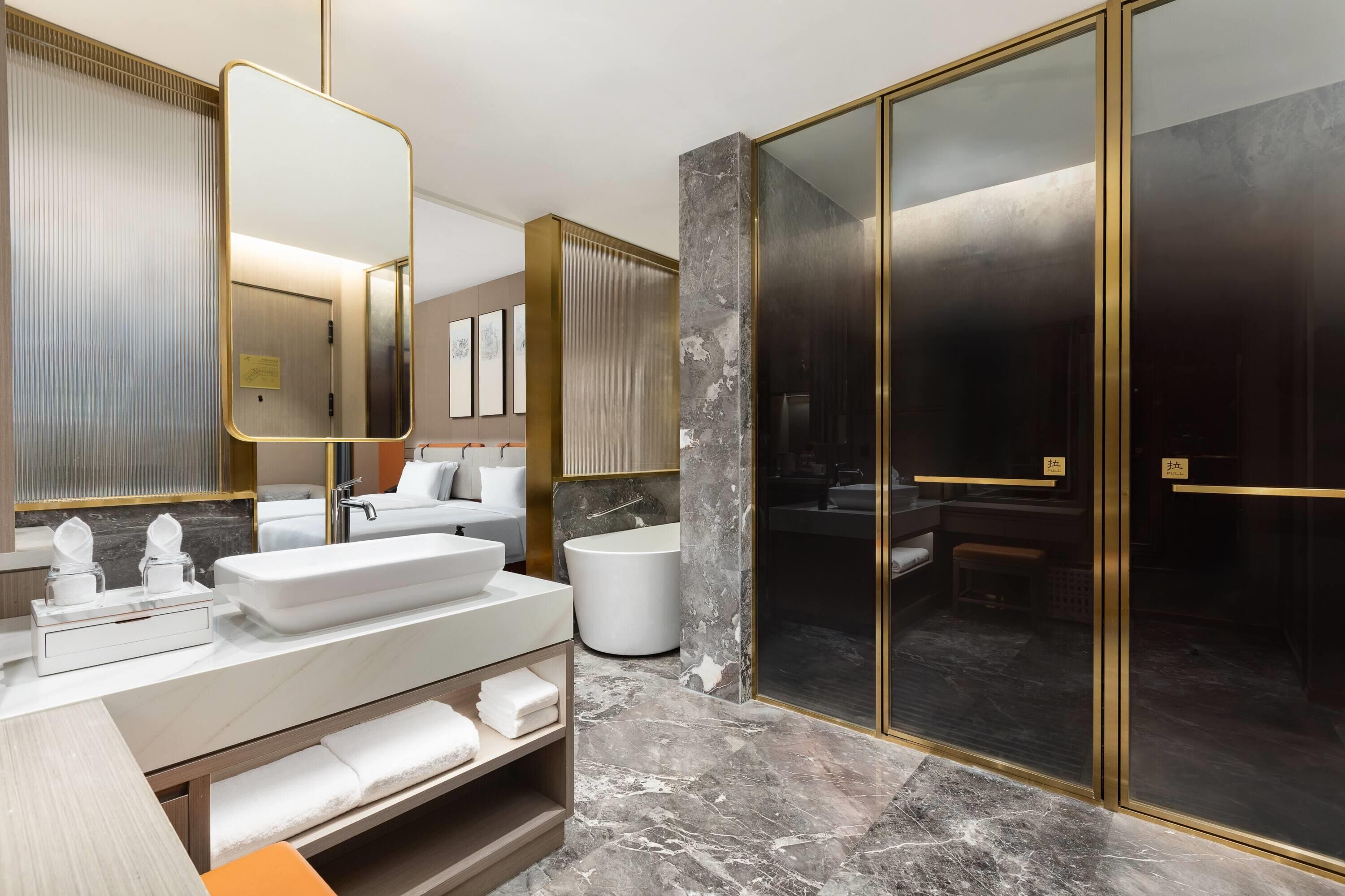 A modern bathroom with a large mirror, a white sink, a bathtub, and a glass-enclosed shower area.