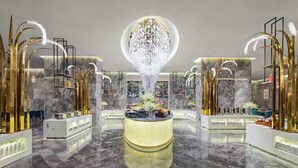 Een luxueuze lobby met een centrale kroonluchter, marmeren vloeren en modern decor.