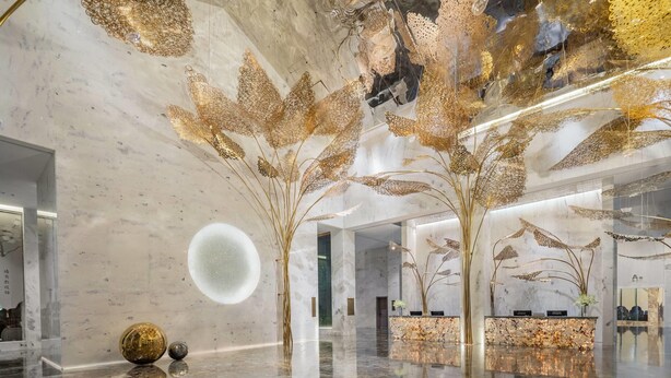 Een moderne lobby met een glanzende marmeren vloer, een receptiebalie en decoratieve muurkunst.