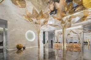 A modern lobby with a reflective marble floor, a reception desk, and decorative wall art. - Wyndham Lijiang Yulong (Lijiang)