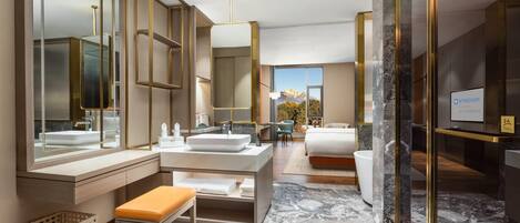 Un baño de hotel moderno con un espejo grande, un lavamanos y un banco.