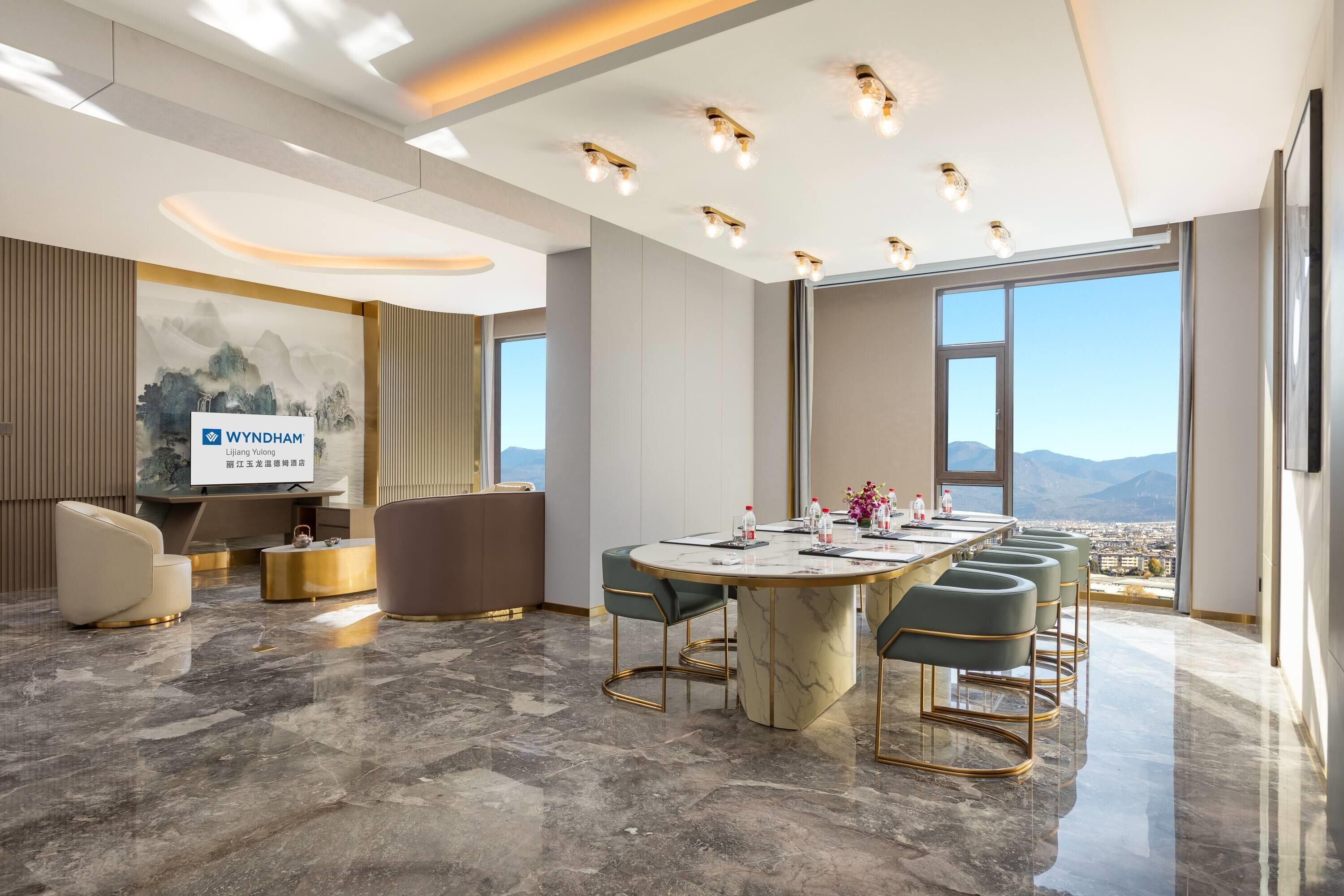 A modern conference room with a marble table, comfortable seating, and a large window offering a city view.