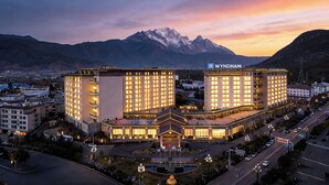 Een hotel met meerdere verdiepingen, een centrale binnenplaats en een berg op de achtergrond.