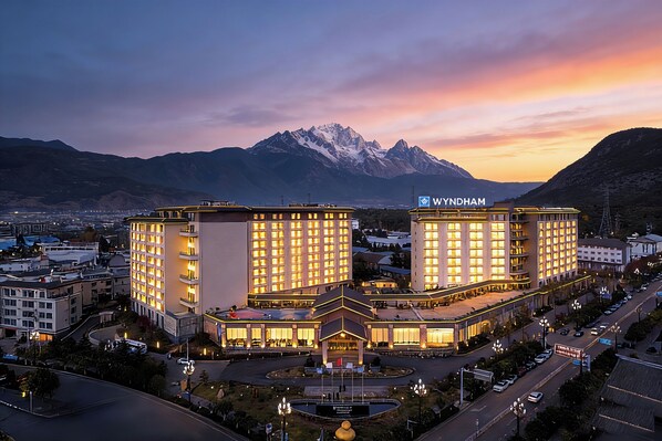 Ein Hotel mit mehreren Etagen, einem zentralen Innenhof und Blick auf die Berge.