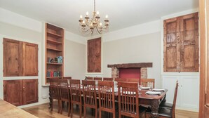 A dining room with a wooden table and chairs, a chandelier, and a brick fireplace. - Norwood House (Ambleside)