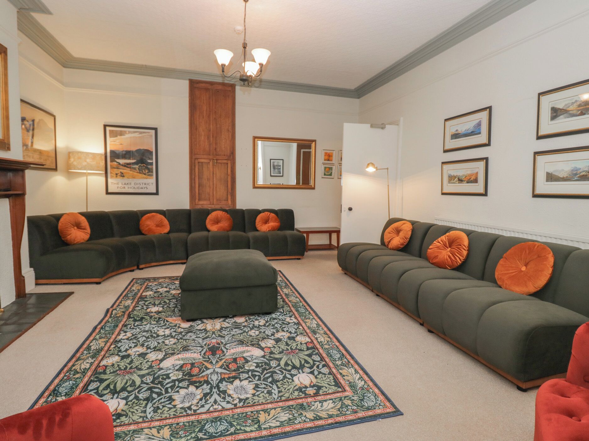 A living room with a green sofa set, a matching ottoman, and a patterned rug.