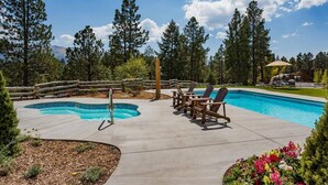 Une piscine dotée de deux bains à remous, entourée de chaises longues en bois et d’une clôture en bois.