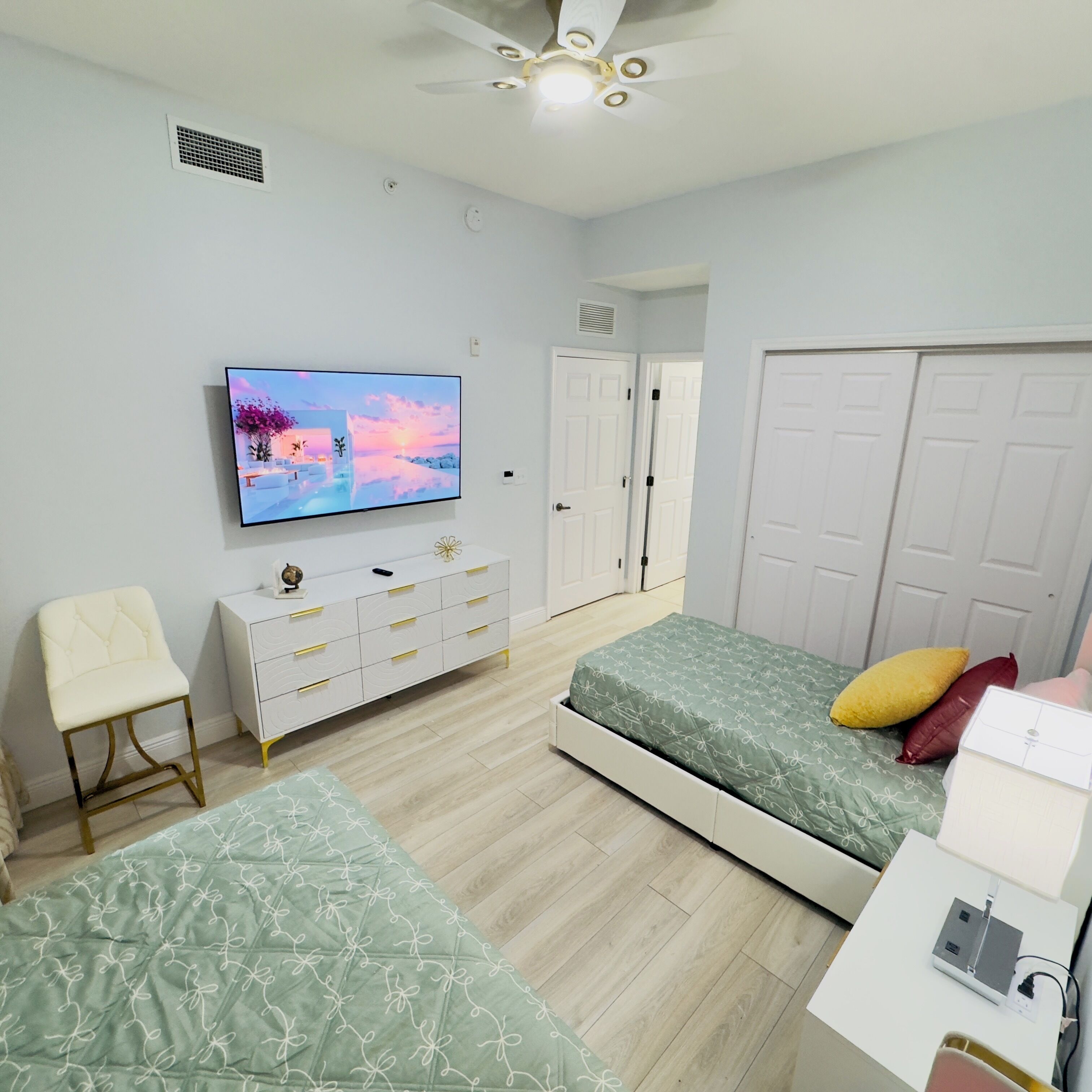 A bedroom with a bed, a TV, a dresser, a chair, and a closet.