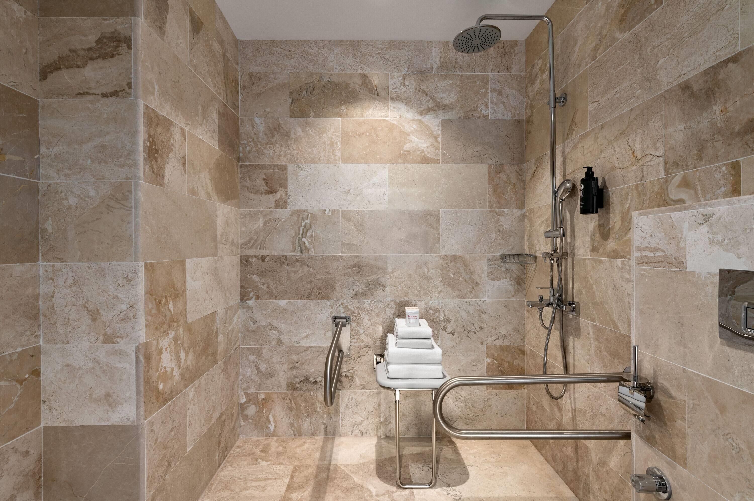 A shower area with a rain showerhead, handheld showerhead, and a handheld shower attachment.