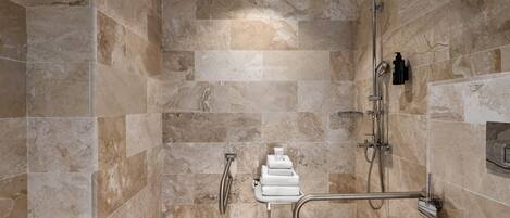 A shower area with a rain showerhead, handheld showerhead, and a handheld shower attachment.