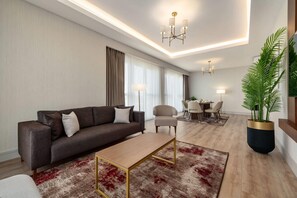 A modern living room with a sofa, coffee table, and a dining area with chairs and a table.