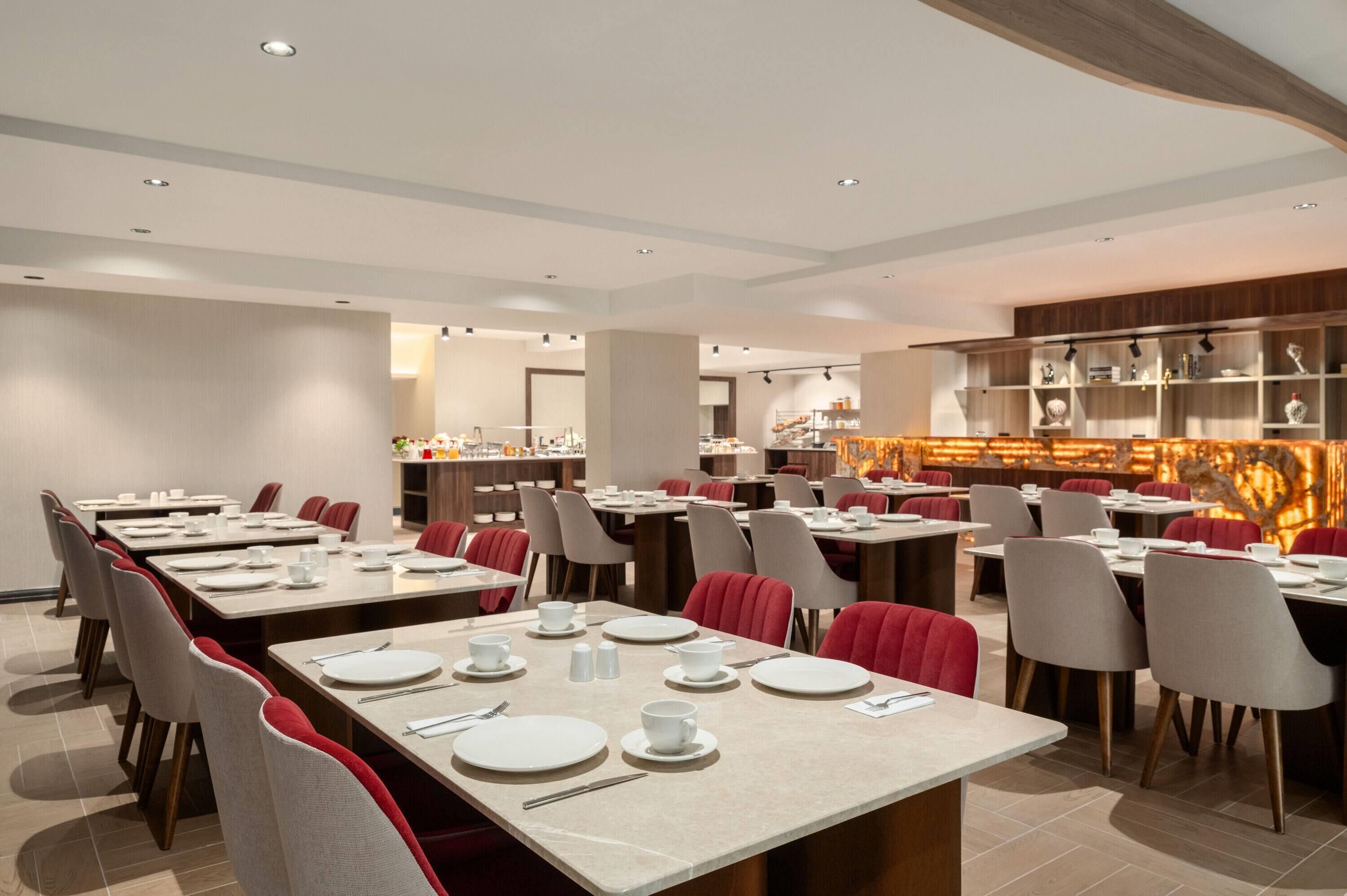 A modern dining area with multiple tables, chairs, and a central decorative wall.