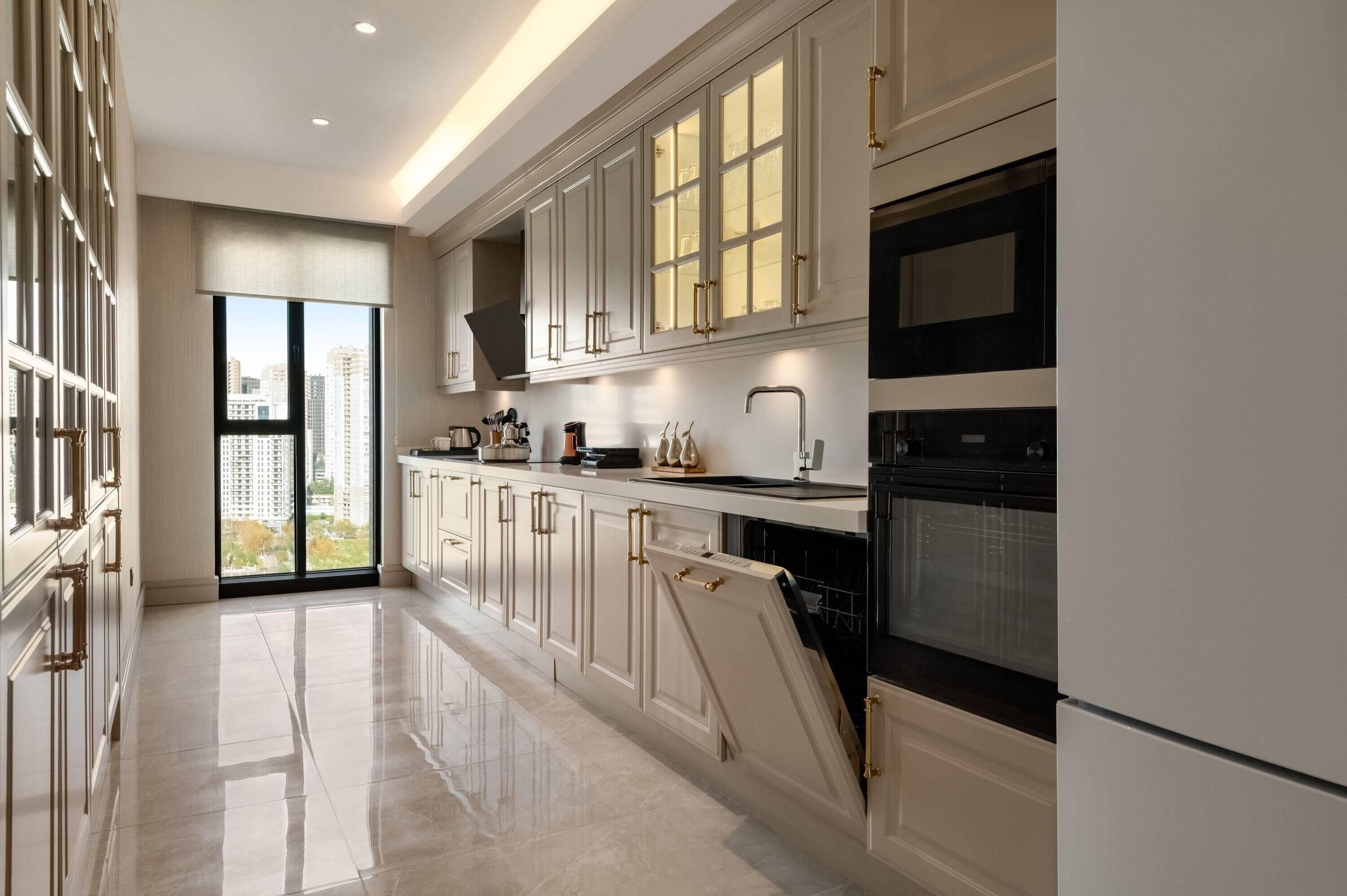 A modern kitchen with white cabinetry, a black oven, and a large window with a city view.