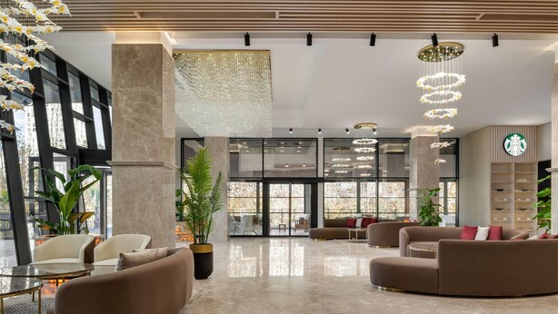 A modern lobby with seating areas, large windows, and a Starbucks sign.