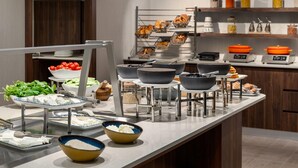 A buffet setup with various food items and serving utensils.