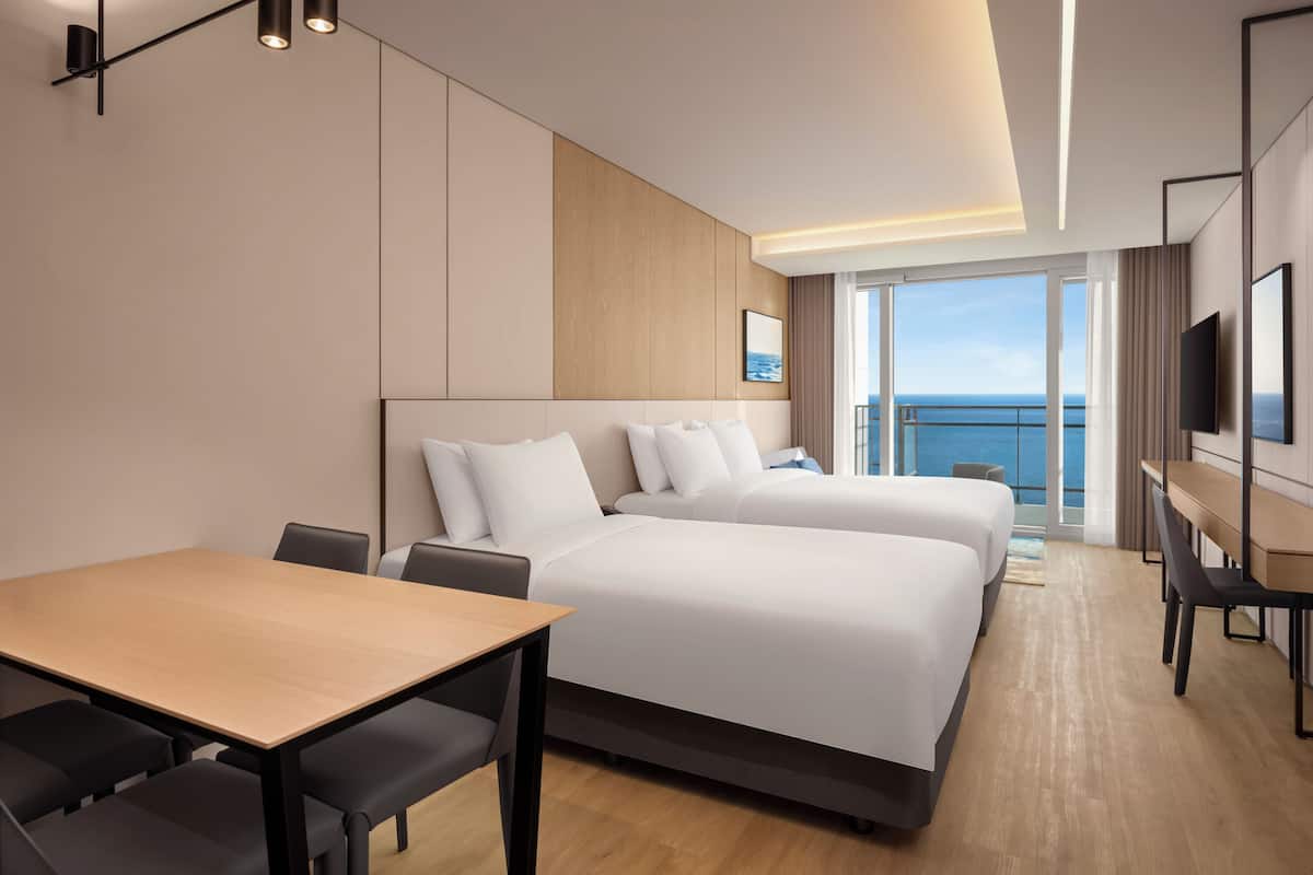 Habitación de hotel moderna con una cama grande, un escritorio y vistas al mar.
