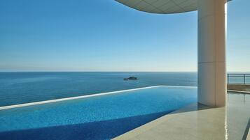 A infinity pool with a clear view of the ocean and a distant island.