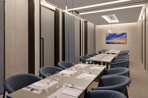 Una sala de conferencias con una mesa larga, sillas y cristalería.
