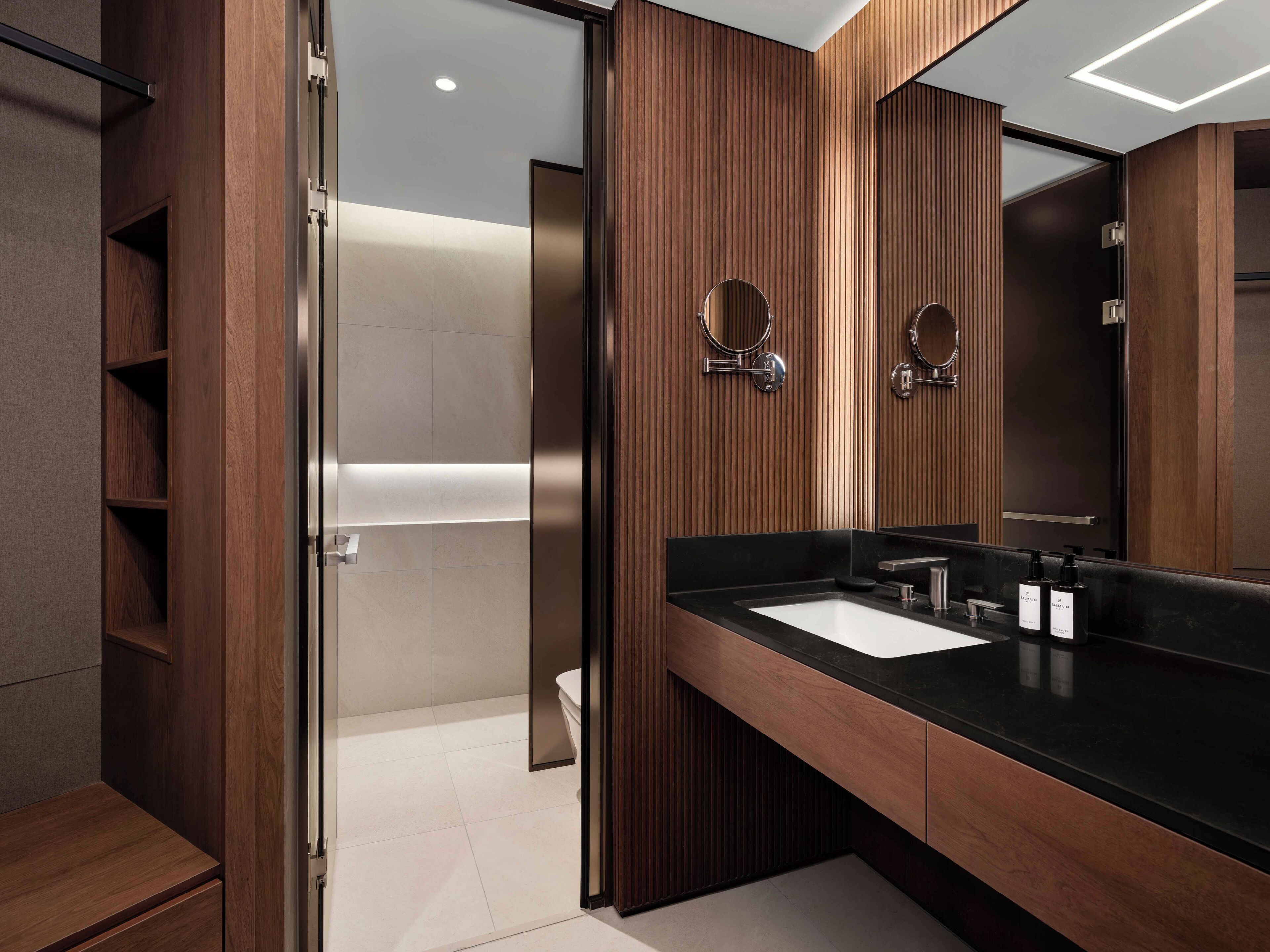 A modern bathroom with a wooden vanity, a large mirror, and a shower area.