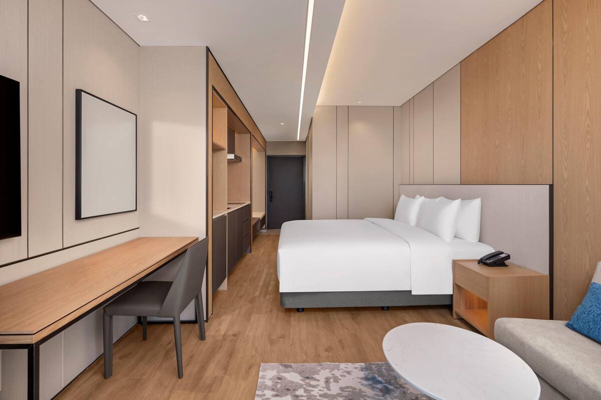 Una habitación de hotel moderna con cama, escritorio, silla y una mesita.