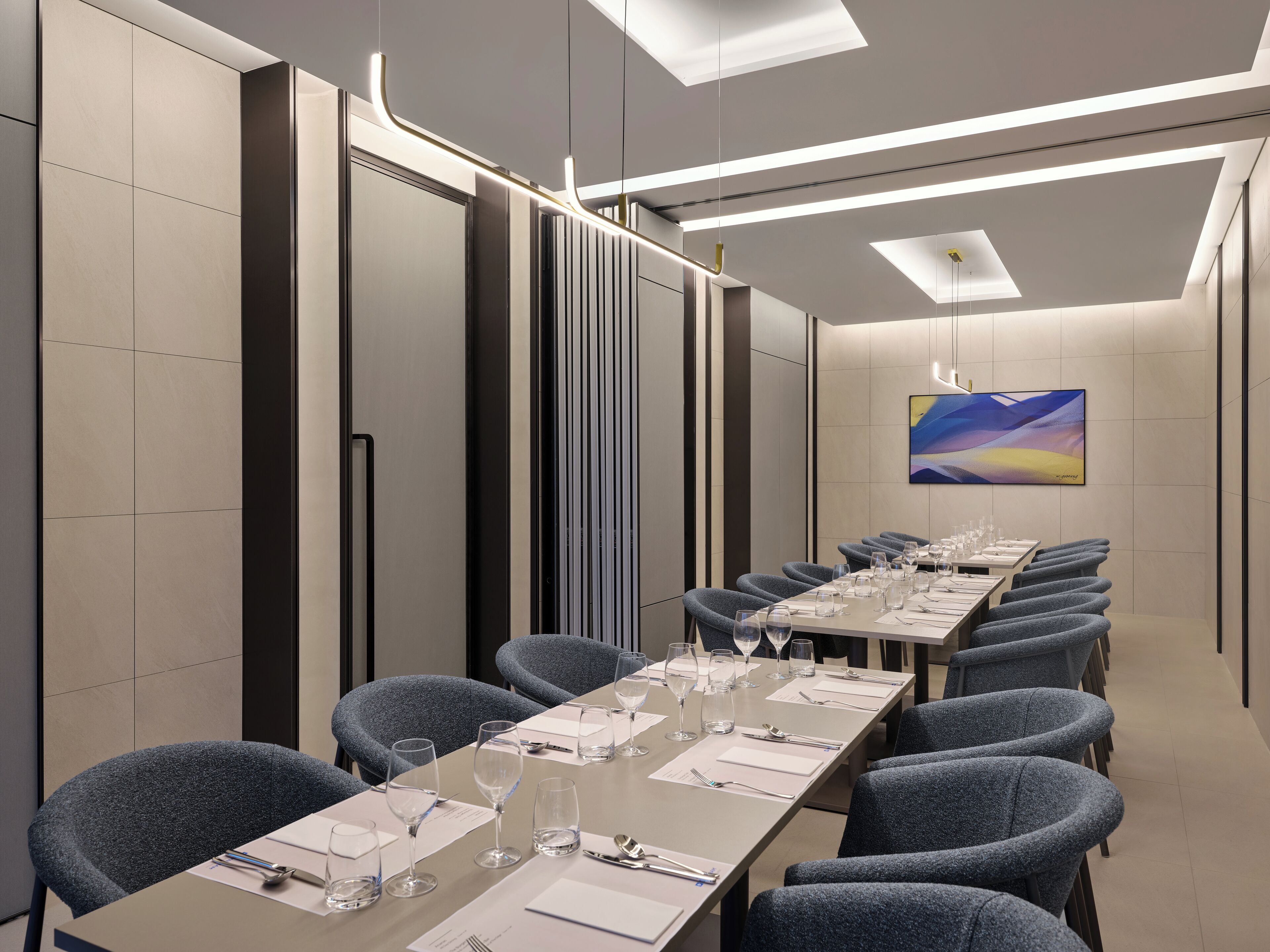 A conference room with a long table, chairs, and a painting on the wall.