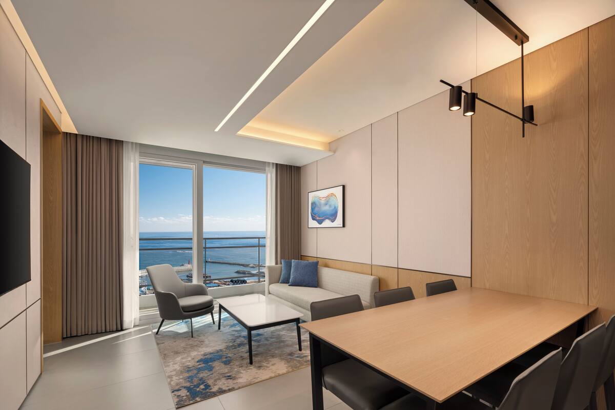 Una habitación de hotel moderna con un balcón grande, un comedor y una sala de estar.