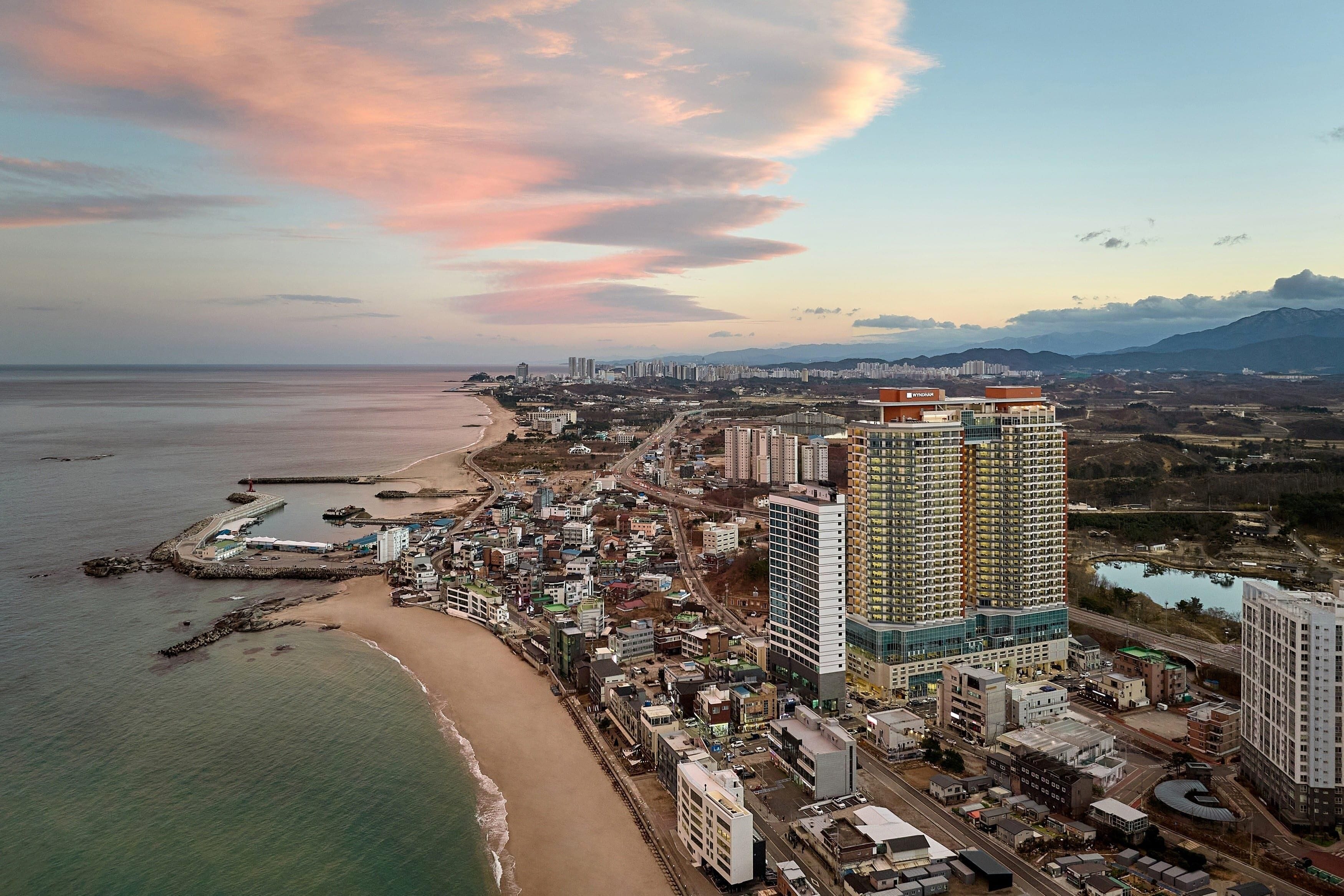 A coastal cityscape with high-rise buildings, a beach, and a marina.