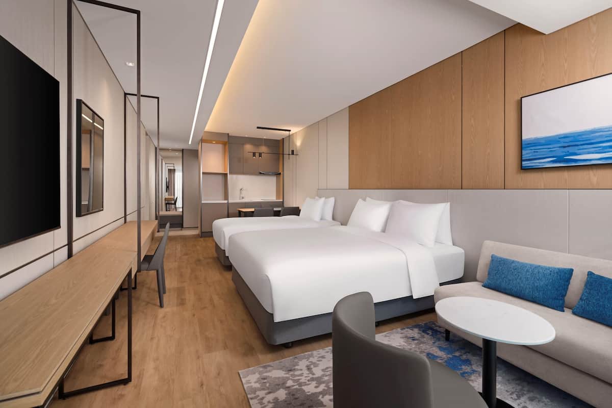 Una habitación de hotel moderna con una cama grande, un sofá, un escritorio y una televisión.