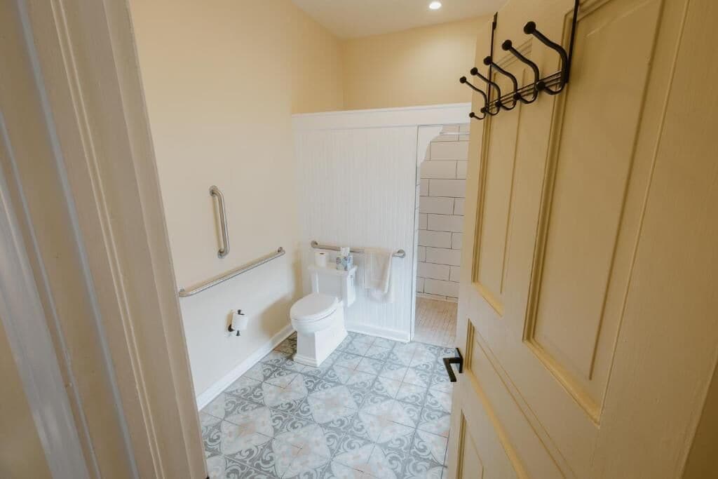 A bathroom with a toilet, a handrail, and a towel rack.