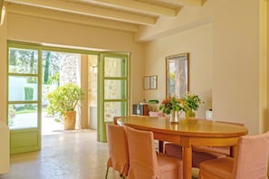 A dining area with a wooden table and chairs, a potted plant, and a framed picture on the wall. - Villa Verde Petra - Three Bedroom Villa, Sleeps 6 (Rethymno)
