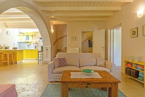 A cozy living room with a sofa, a wooden coffee table, and a bookshelf. - Villa Verde Petra - Three Bedroom Villa, Sleeps 6 (Rethymno)