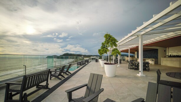 Terraço no telhado com área de estar externa, piscina e vista para o mar.