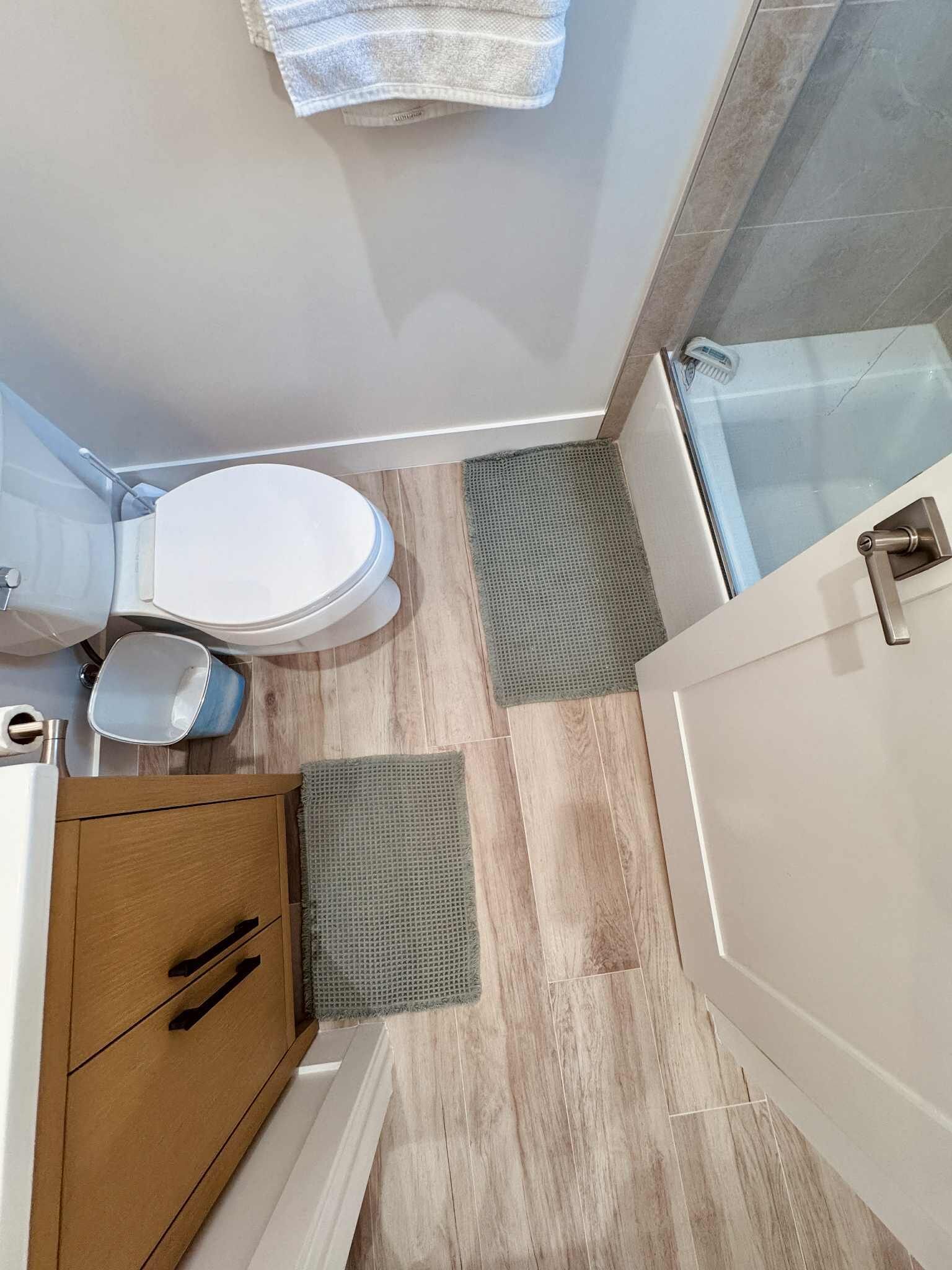 A bathroom with a toilet, wooden cabinet, and a shower area.