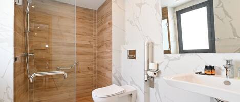 Un baño moderno con ducha de vidrio, inodoro blanco y lavamanos de mármol.