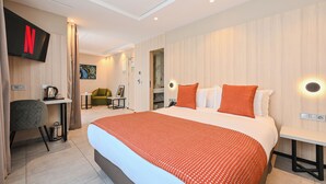 A modern hotel room with a large bed, a desk, a chair, a TV, and a painting on the wall. - Boutique Hotel Aruba Casablanca (Casablanca)