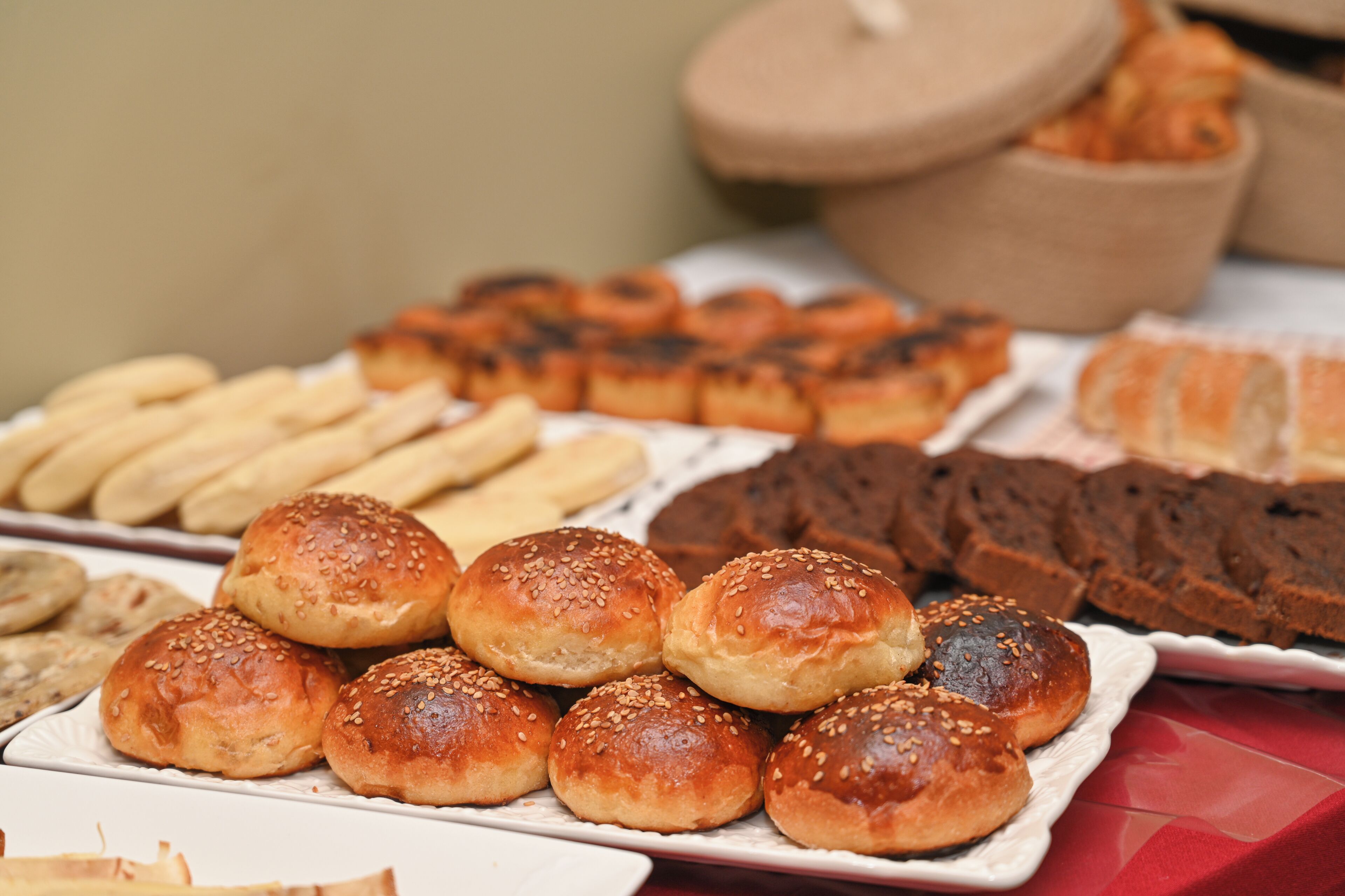 Variedad de productos horneados, incluyendo panecillos y pastelería, sobre una mesa.
