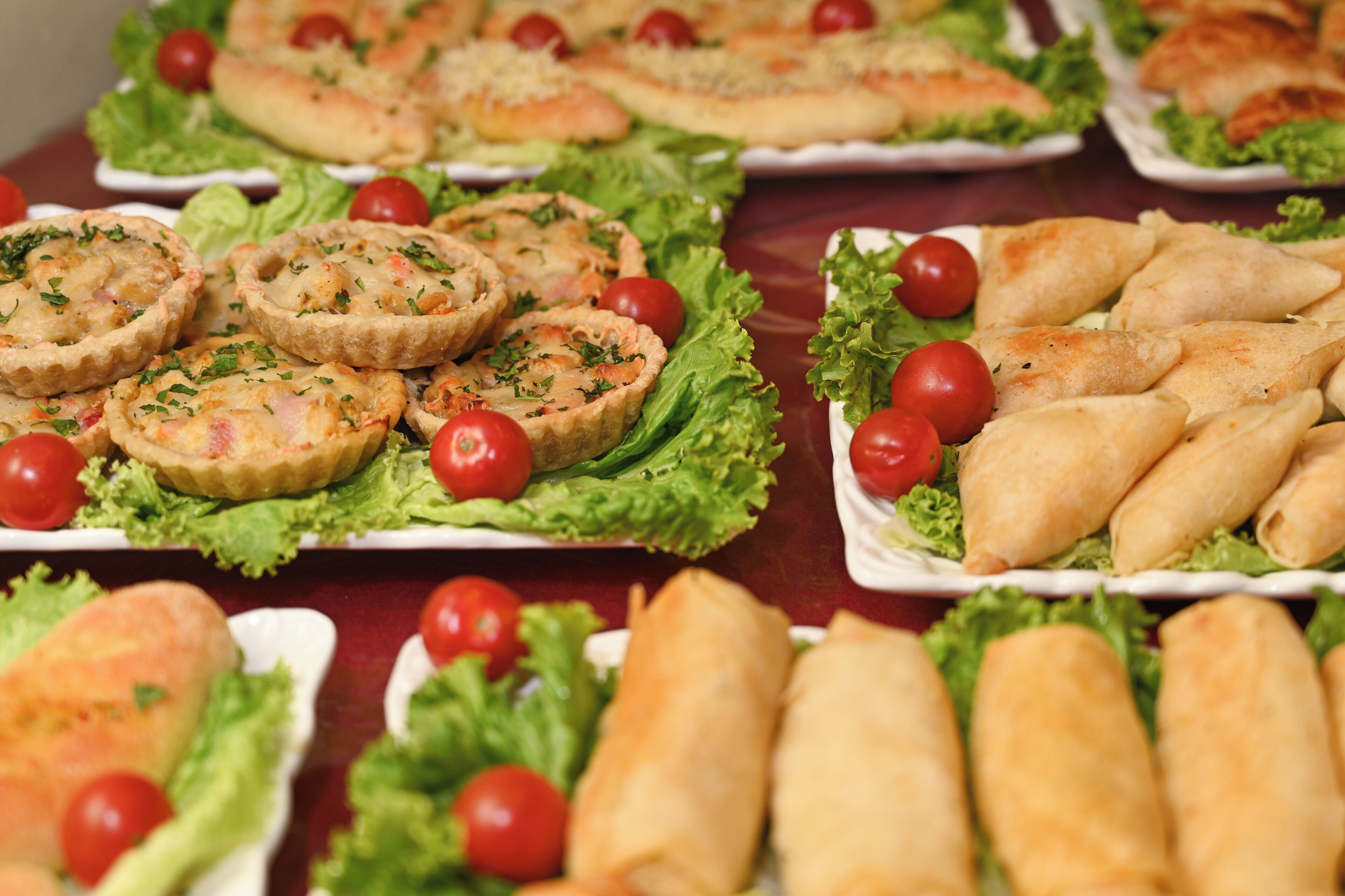 A variety of appetizers arranged on plates with lettuce and cherry tomatoes.
