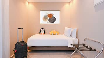 A hotel room with a bed, a framed artwork on the wall, a luggage trolley, and a bench.