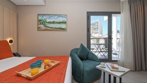 A hotel room with a bed, breakfast tray, teal armchair, and a table with a laptop. - Boutique Hotel Aruba Casablanca (Casablanca)